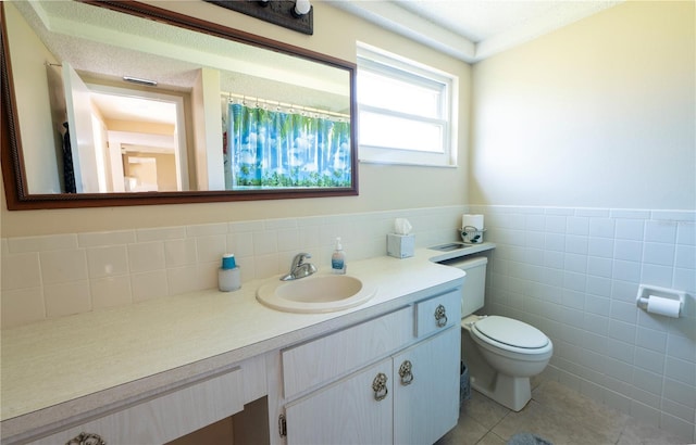 full bathroom featuring wainscoting, toilet, tile patterned flooring, vanity, and tile walls