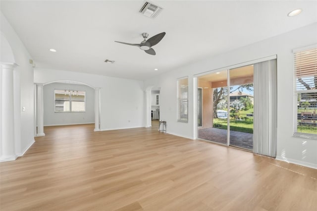 unfurnished living room with decorative columns, light hardwood / wood-style flooring, ceiling fan, and plenty of natural light