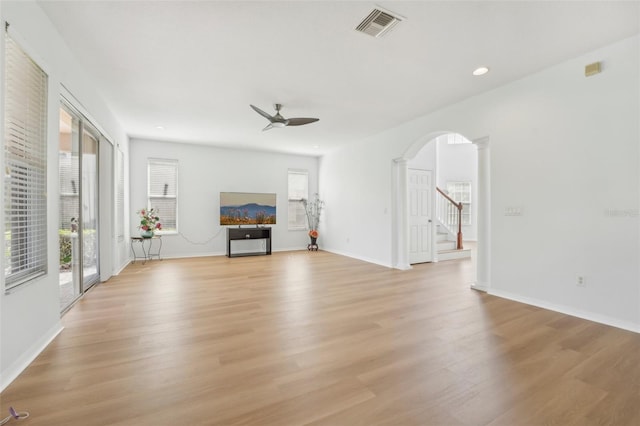 unfurnished living room with ornate columns, light wood-type flooring, and ceiling fan