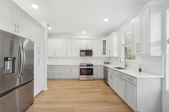 kitchen with white cabinetry, appliances with stainless steel finishes, sink, and light wood-type flooring