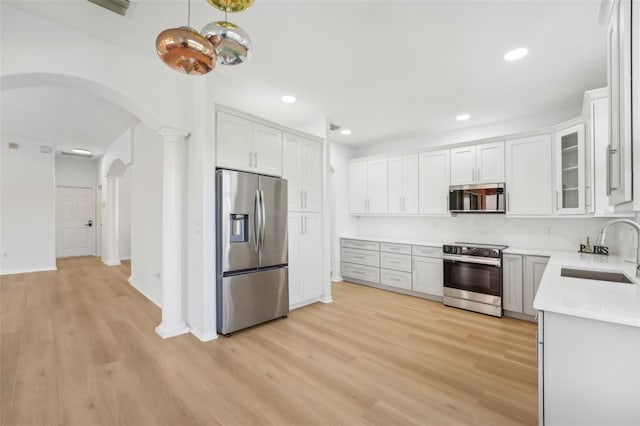 kitchen with sink, appliances with stainless steel finishes, light hardwood / wood-style flooring, and white cabinetry