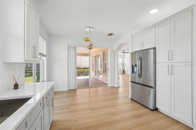 18051 Java Isle Dr, Tampa, FL 33647 - kitchen featuring stainless steel fridge with ice dispenser, light wood-type flooring, arched walkways, decorative light fixtures, and white cabinets