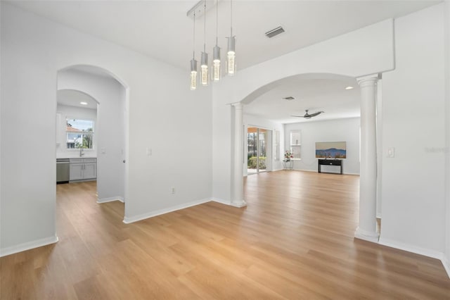 interior space with ceiling fan, decorative columns, and light hardwood / wood-style flooring