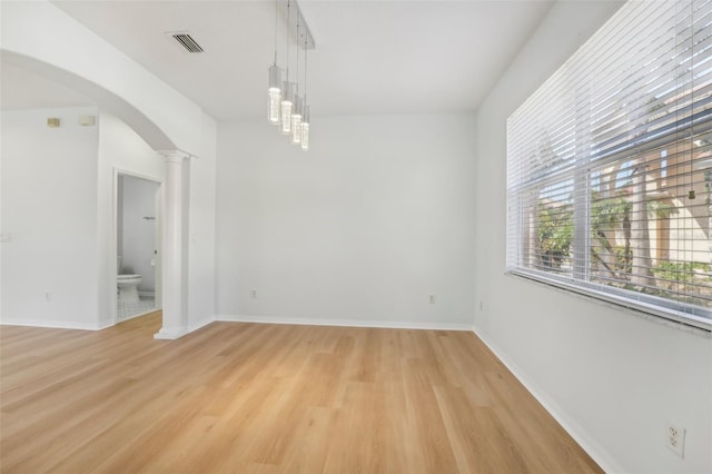 spare room featuring ornate columns and light hardwood / wood-style floors