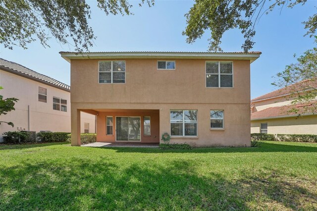 18051 Java Isle Dr, Tampa, FL 33647 - rear view of house featuring stucco siding and a lawn