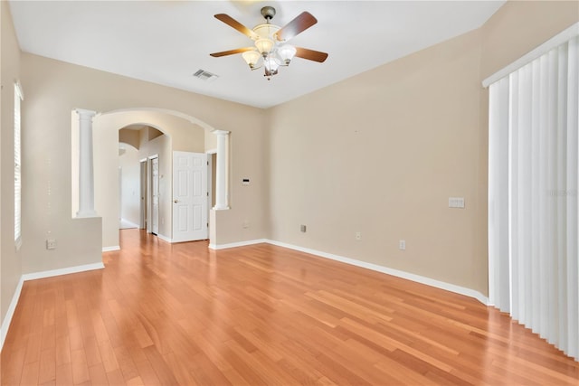 spare room with ceiling fan, decorative columns, and light hardwood / wood-style flooring