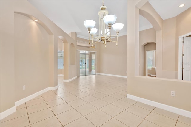 tiled empty room featuring a notable chandelier and french doors