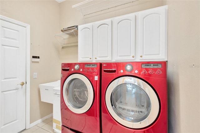 washroom with cabinets, light tile patterned flooring, and washing machine and clothes dryer