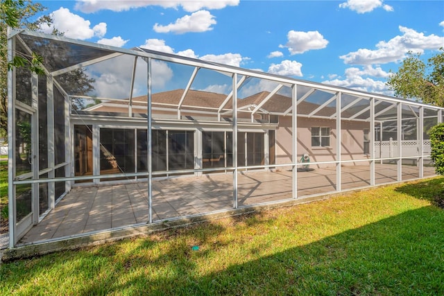 back of property with a patio area, a lawn, a pool, and glass enclosure