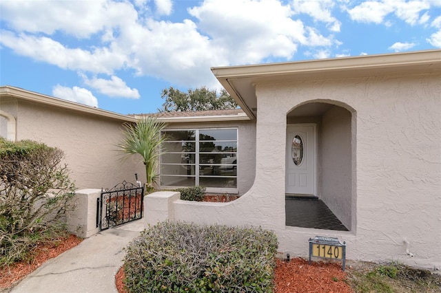 entrance to property with stucco siding and a gate