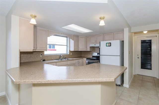 kitchen with a sink, under cabinet range hood, stainless steel electric stove, freestanding refrigerator, and a peninsula