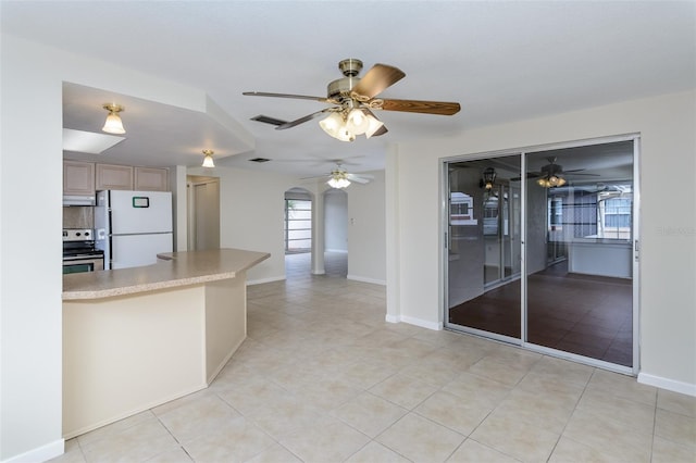 kitchen featuring arched walkways, stainless steel range with electric stovetop, freestanding refrigerator, and a ceiling fan