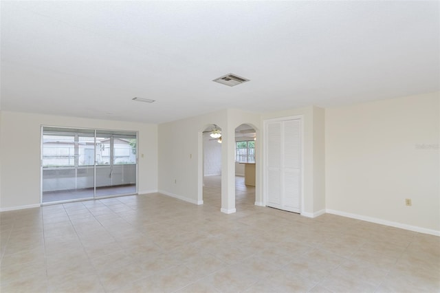 unfurnished room featuring visible vents, baseboards, arched walkways, and ceiling fan