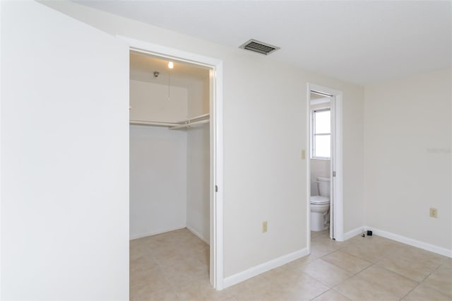 unfurnished bedroom with visible vents, ensuite bathroom, a closet, light tile patterned floors, and baseboards