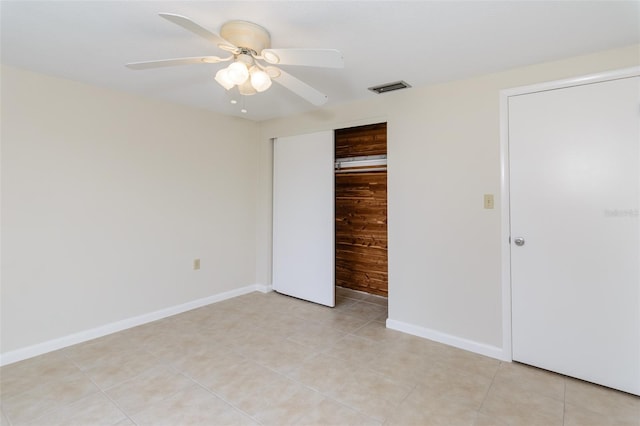 unfurnished bedroom featuring visible vents, baseboards, light tile patterned flooring, a closet, and a ceiling fan