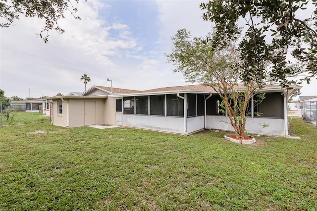 back of house featuring a lawn, fence, and a sunroom