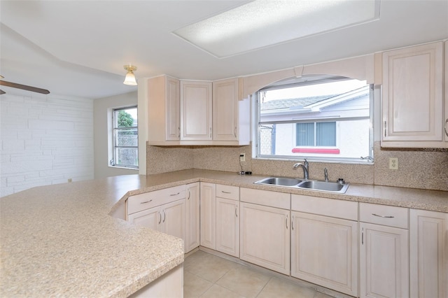 kitchen featuring tasteful backsplash, ceiling fan, light countertops, light tile patterned flooring, and a sink