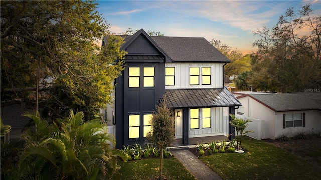 modern inspired farmhouse featuring a lawn, board and batten siding, metal roof, and a standing seam roof