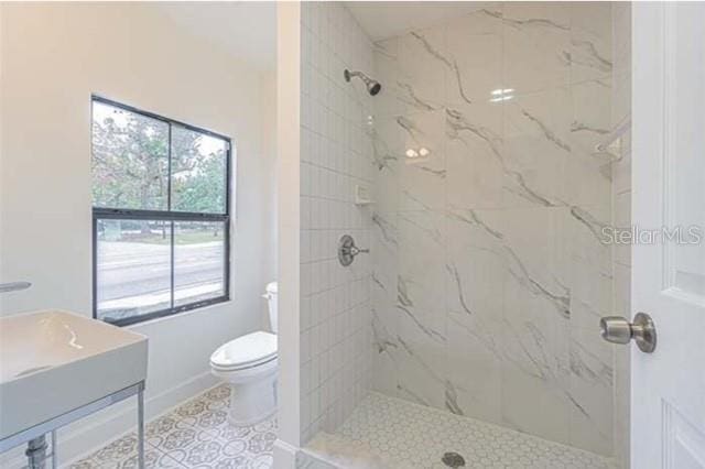 bathroom with toilet, vanity, tile patterned floors, and tiled shower