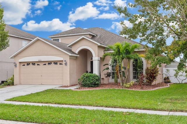 30552 Latourette Dr, Wesley Chapel, FL 33545 - view of front facade featuring an attached garage, concrete driveway, stucco siding, a front lawn, and roof with shingles