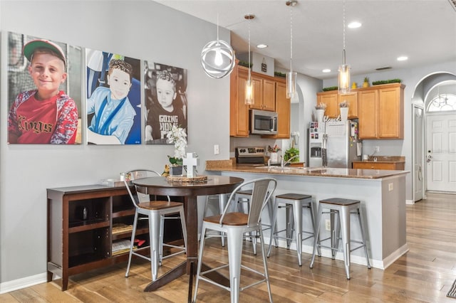 30552 Latourette Dr, Wesley Chapel, FL 33545 - kitchen with stainless steel appliances, arched walkways, light wood-type flooring, a breakfast bar area, and recessed lighting