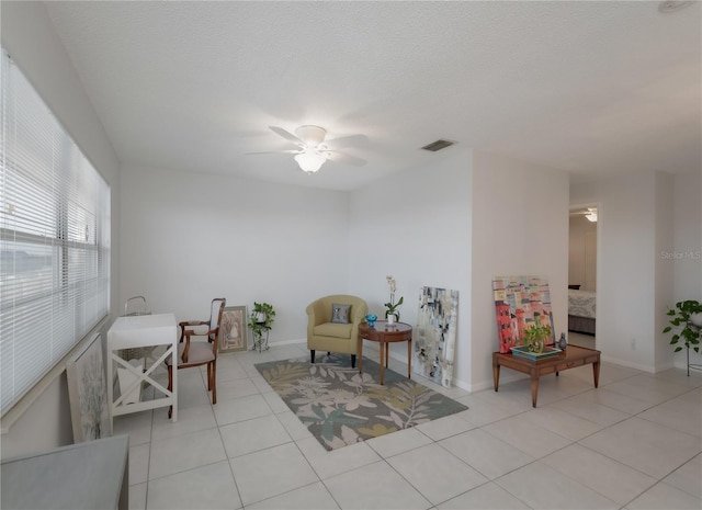 sitting room featuring ceiling fan, light tile patterned floors, and a textured ceiling