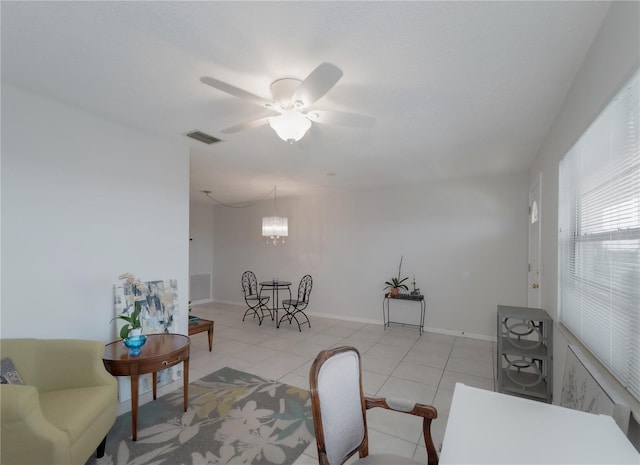 tiled living room with ceiling fan with notable chandelier