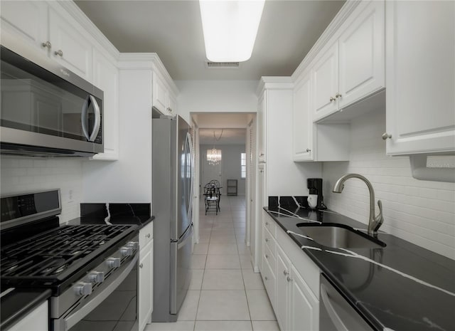 kitchen with white cabinets, sink, decorative backsplash, light tile patterned floors, and appliances with stainless steel finishes