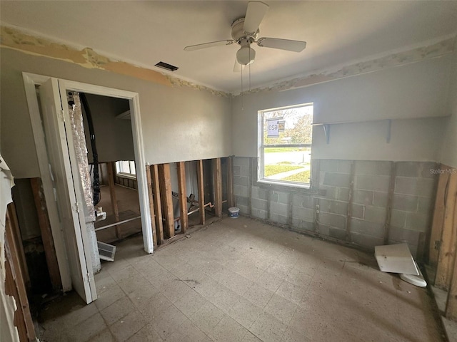 unfurnished room featuring tile walls and ceiling fan