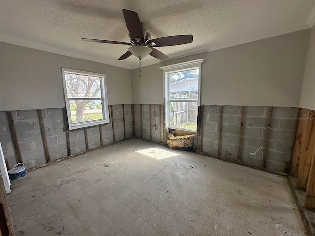 empty room with a textured ceiling, a healthy amount of sunlight, and ceiling fan