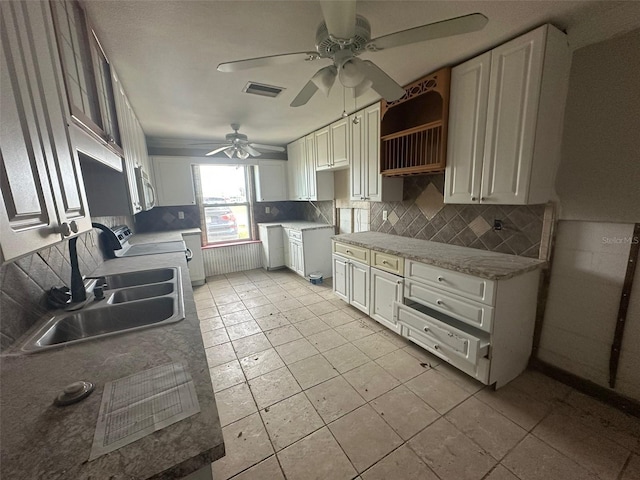 kitchen featuring decorative backsplash, ceiling fan, white cabinetry, stove, and sink