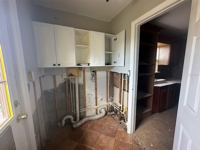 clothes washing area with hookup for a washing machine, cabinets, and dark tile patterned floors