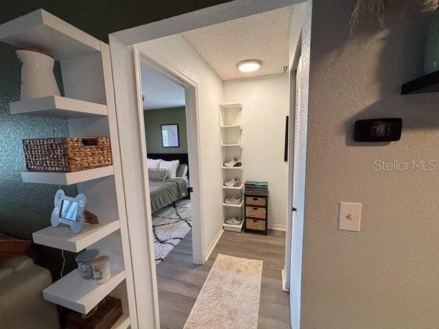 corridor featuring light hardwood / wood-style flooring and a textured ceiling