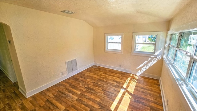 empty room featuring a textured ceiling, vaulted ceiling, and dark hardwood / wood-style floors