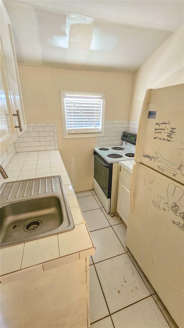 kitchen with sink, white appliances, and light tile patterned floors