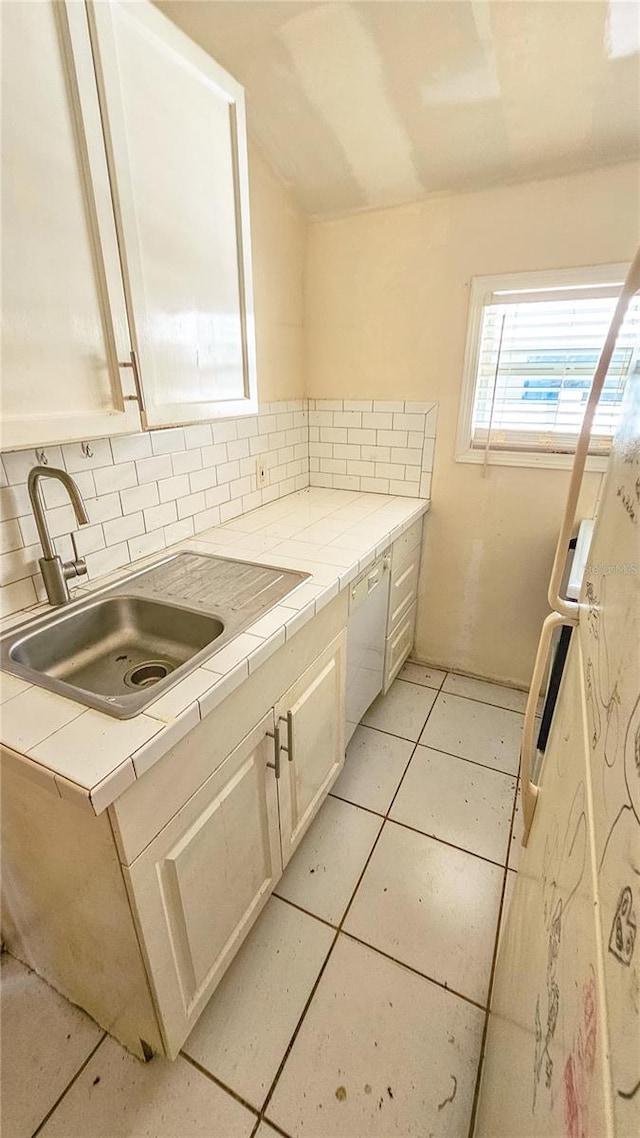 kitchen with sink, tile countertops, light tile patterned flooring, and backsplash