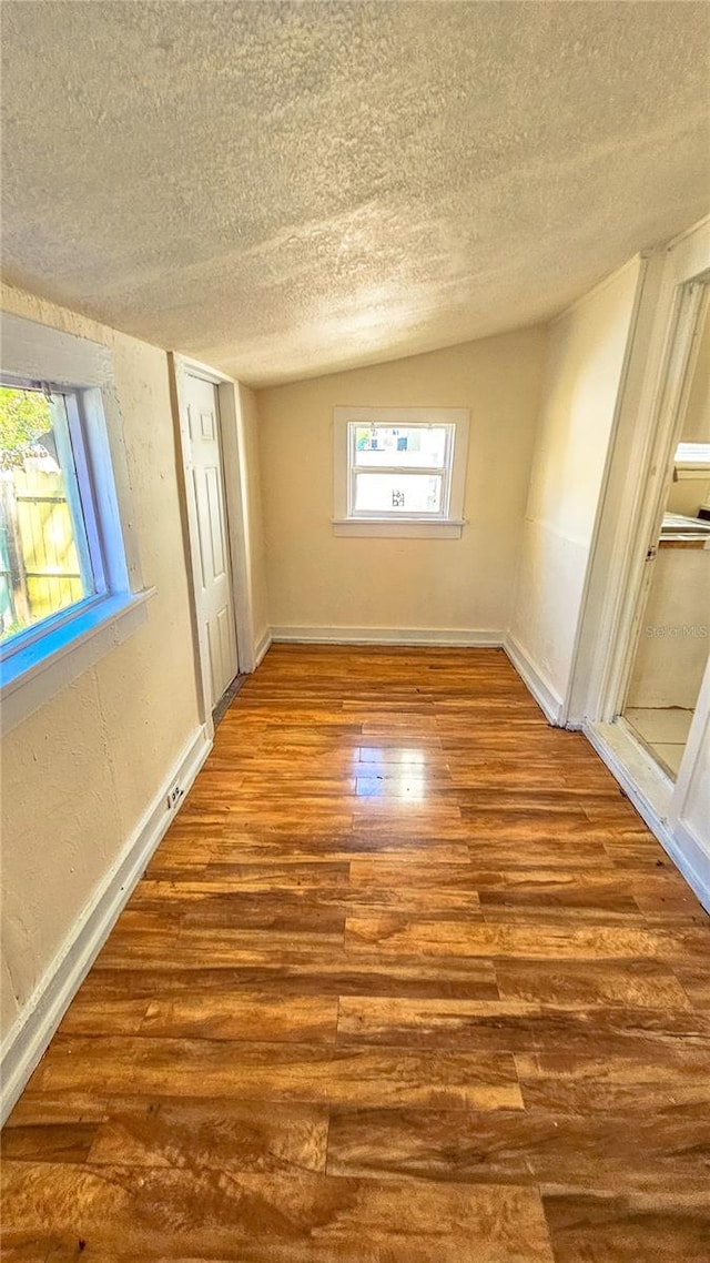 unfurnished bedroom with lofted ceiling, hardwood / wood-style floors, and a textured ceiling