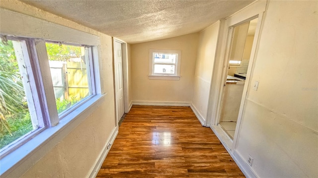 hallway featuring lofted ceiling, dark wood-type flooring, and a textured ceiling