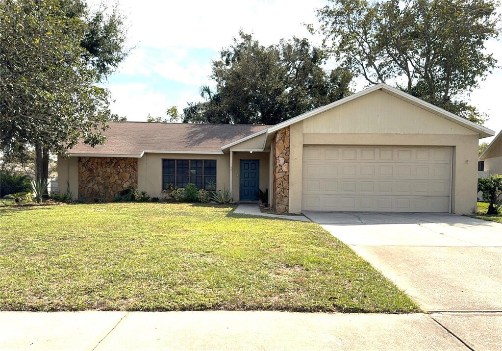 ranch-style house with a garage, driveway, stone siding, and a front yard