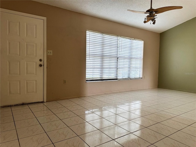 foyer entrance featuring a textured ceiling, light tile patterned flooring, and ceiling fan