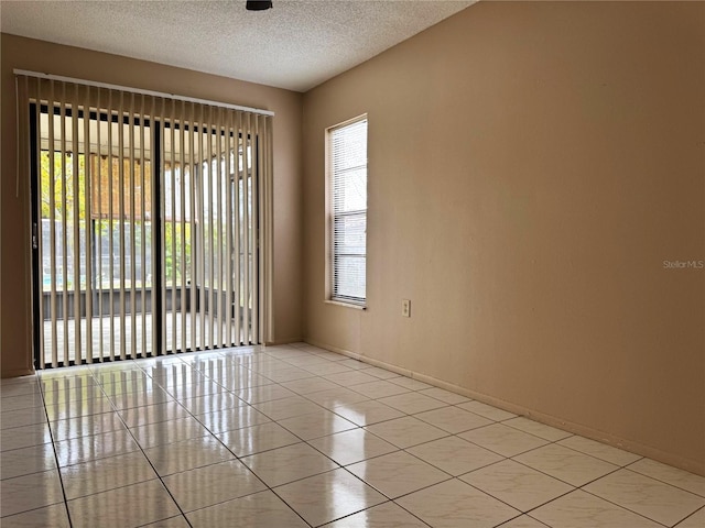 tiled empty room featuring a textured ceiling