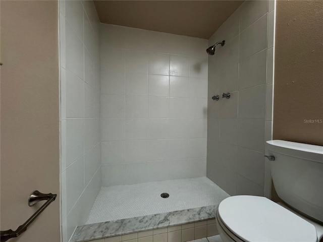 bathroom featuring a tile shower and toilet