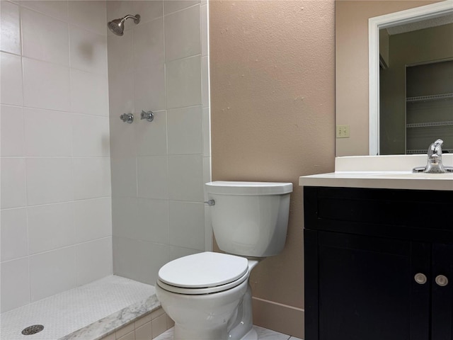 bathroom featuring toilet, vanity, and tiled shower