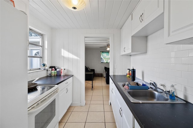205 Santurce Ave, North Port, FL 34287 - kitchen with a sink, dark countertops, a wealth of natural light, white appliances, and light tile patterned flooring