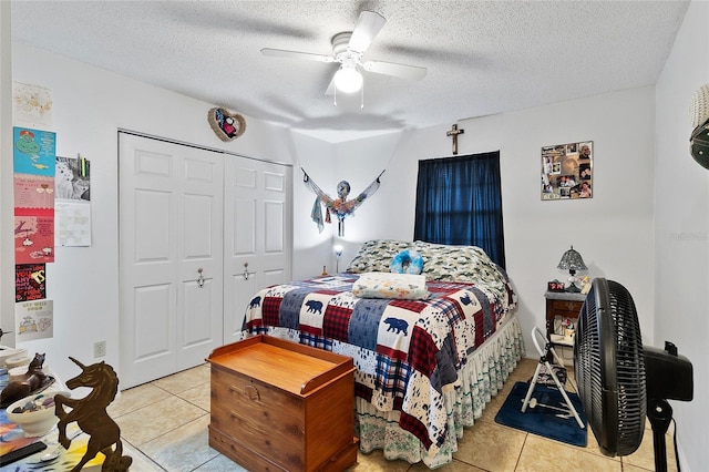 bedroom with light tile patterned floors, a closet, a textured ceiling, and ceiling fan