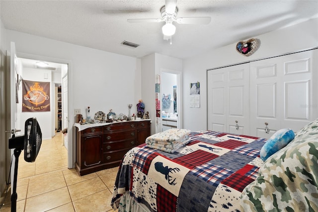 tiled bedroom with ceiling fan, a closet, and a textured ceiling