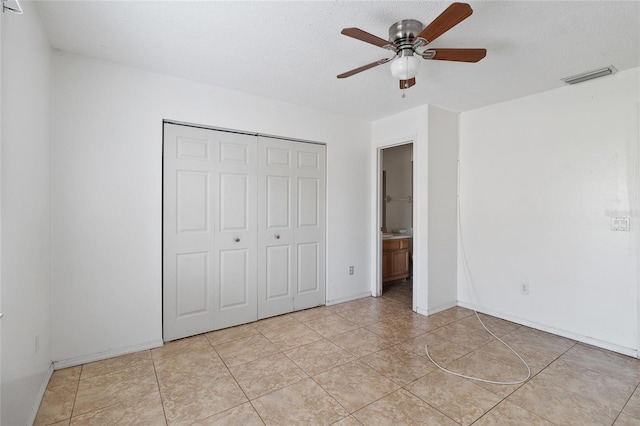 unfurnished bedroom featuring light tile patterned floors, a closet, a textured ceiling, and ceiling fan