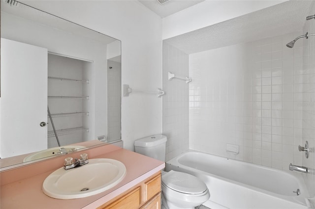 full bathroom featuring tiled shower / bath, vanity, toilet, and a textured ceiling