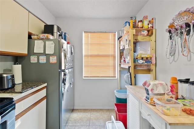 kitchen with light tile patterned flooring, wood counters, stainless steel appliances, and a textured ceiling