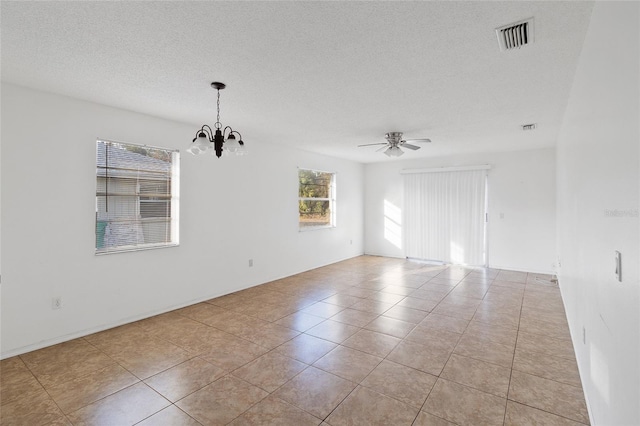 empty room featuring ceiling fan with notable chandelier, a textured ceiling, and light tile patterned floors